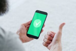 Man holding an android phone with a green tick on the screen.