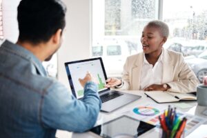 Smiling female discussing customer analytics with her male colleague.