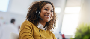 Customer service representative answering the telephone with a headset on, smiling whilst talking to a customer