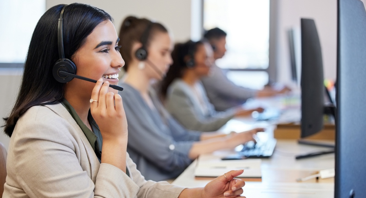 Female customer service agent in an office environment smiling while on the phone to a customer.